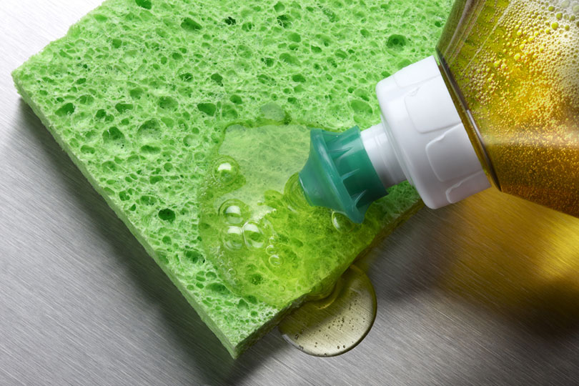 macro shot of dish soap being squeezed onto green sponge