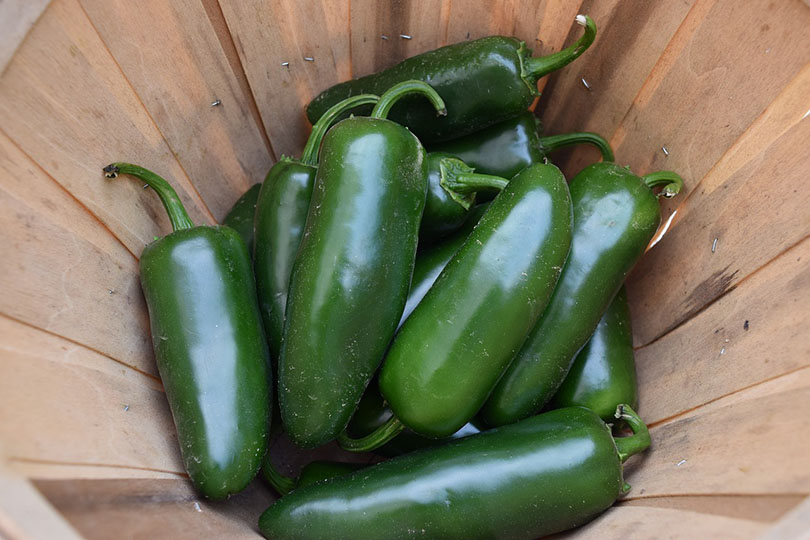 green jalapeños in a wooden basket