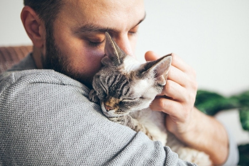 Un hombre abrazando a su gato.