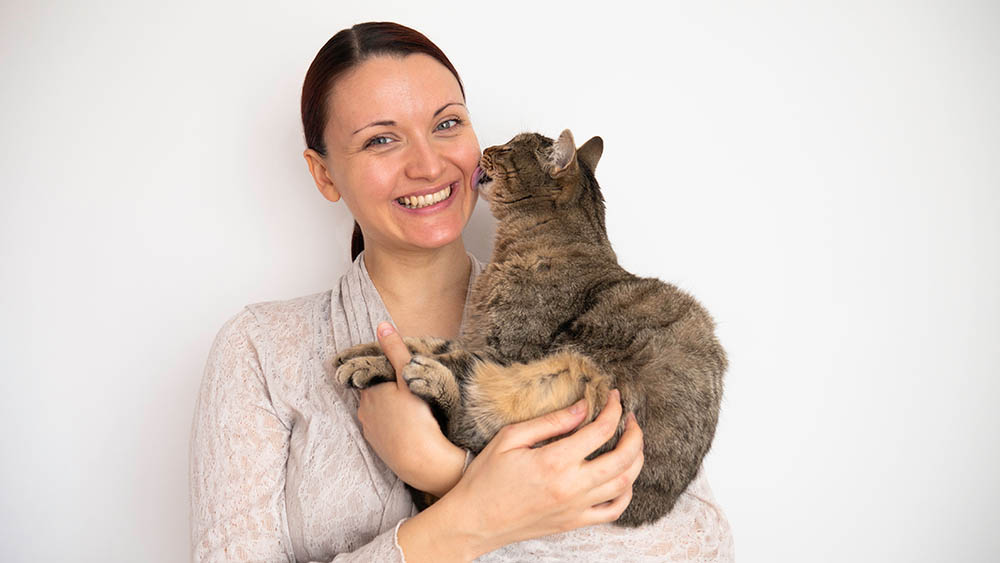 cat licking woman's ear