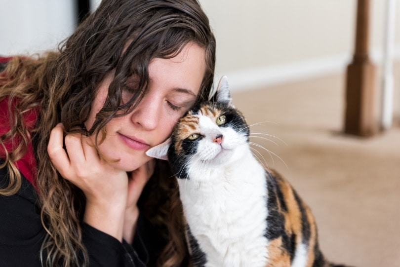 woman bonding with calico cat