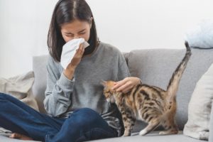 woman sneezing while holding a cat