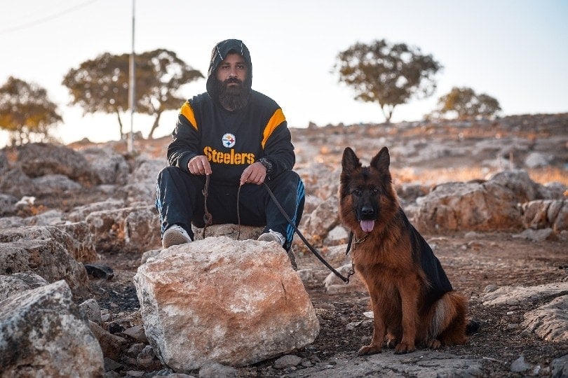 man oudoors with his german shepherd pet