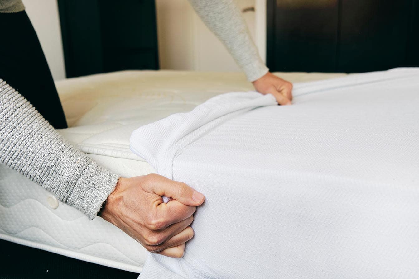 person covering mattress with protector