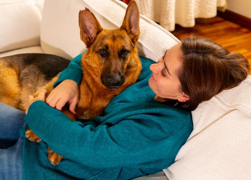 smiling woman hugging her german shepherd dog