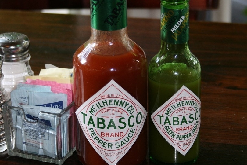 Two bottles of hot sauce on table