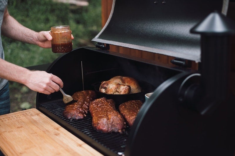 barbecue sauce being brushed on ribs on the grill