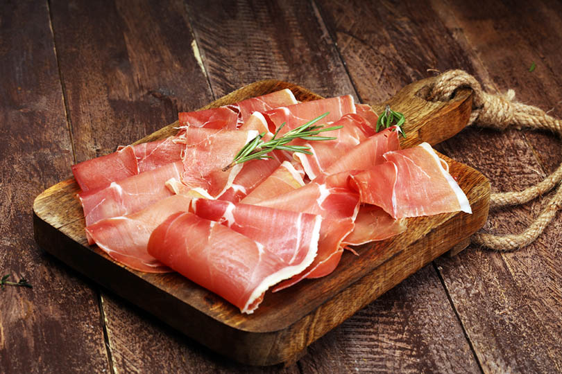 Rebanadas de jamón crudo en una tabla de madera.