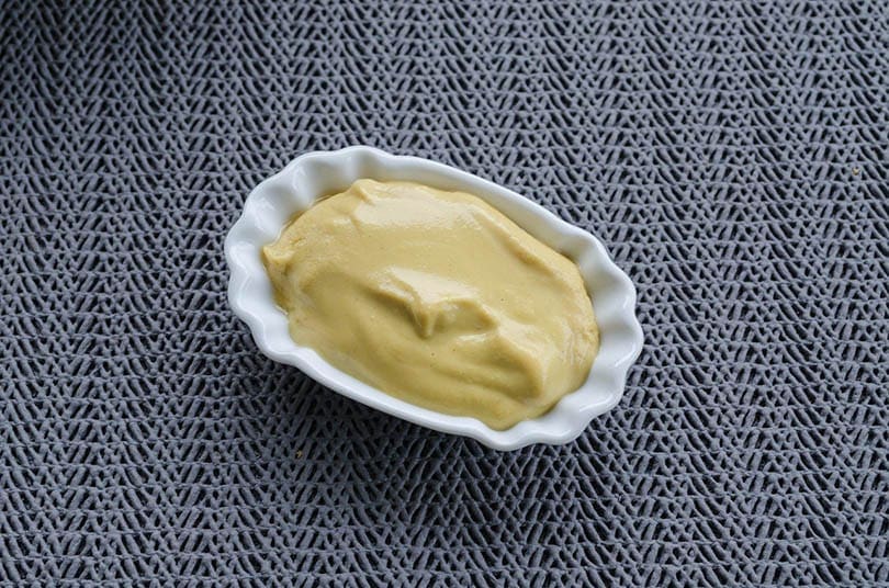 yellow mustard on a white saucer