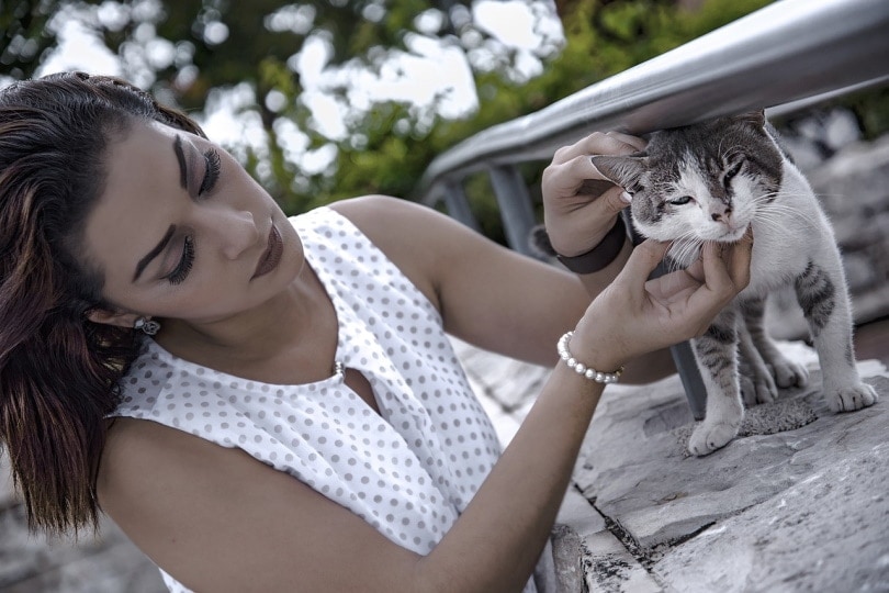 Young woman picking up a lost cat