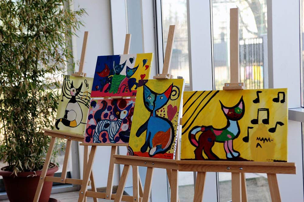 three cat canvas paintings in a gallery