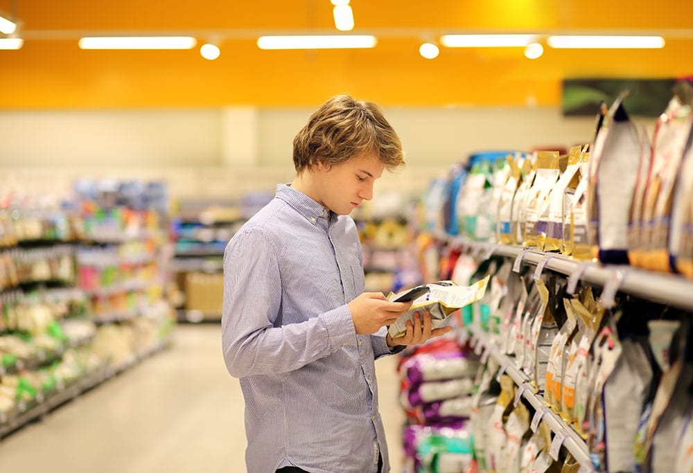 Hombre joven mirando comida para perro en el supermercado.