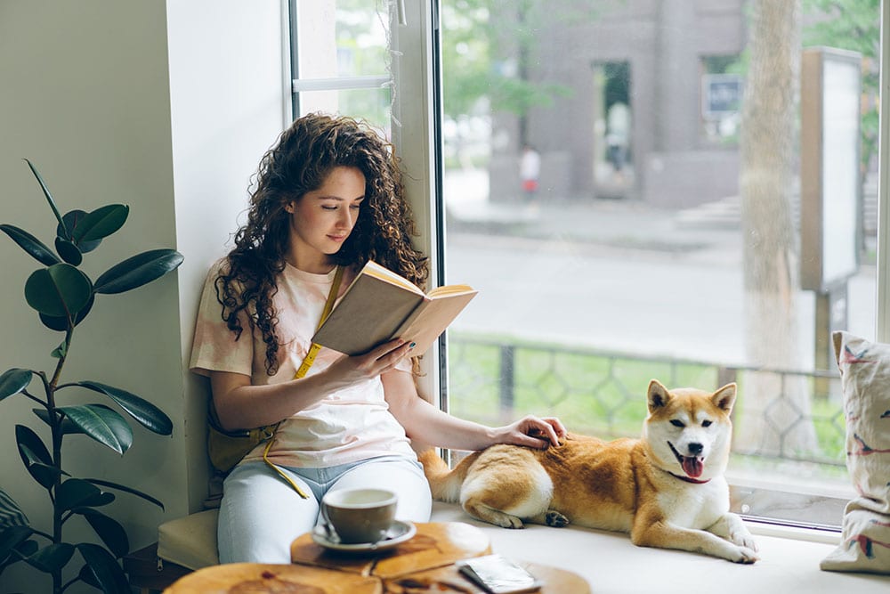 Pretty girl is reading book with shiba inu