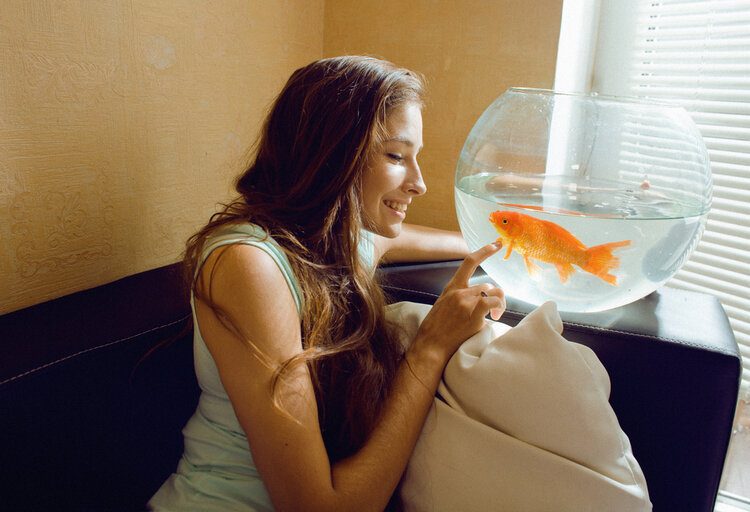woman playing with pet goldfish