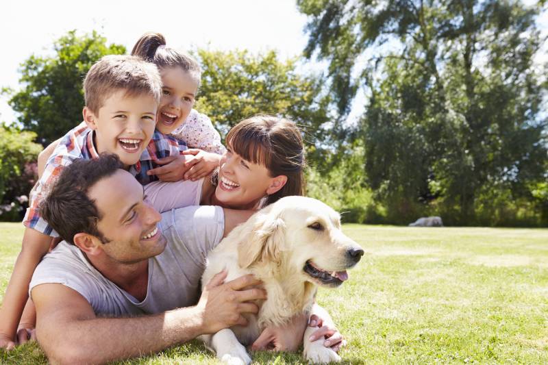 family relaxing In garden with pet dog