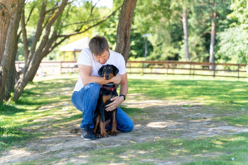 man spending time with his doberman dog outdoors