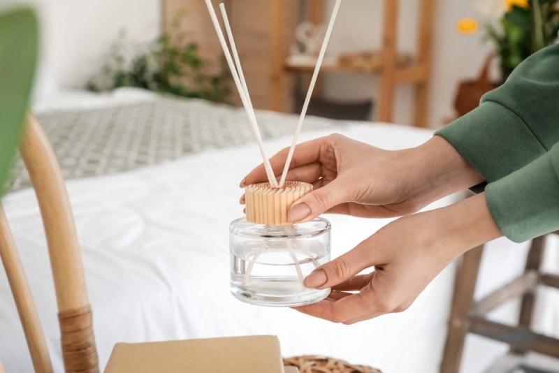 người phụ nữ cầm máy khuếch tán sậy