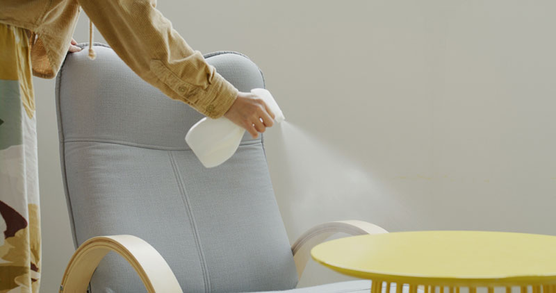 a woman spraying the furnitures at home