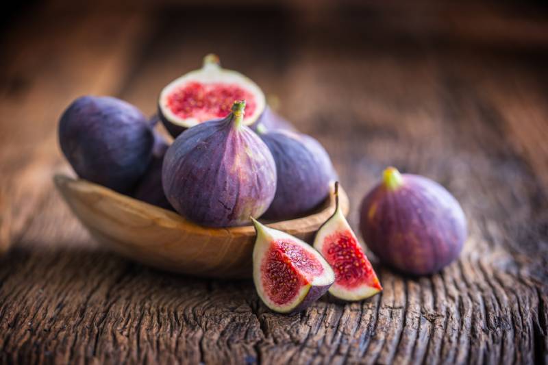 few figs in a bowl on an old wooden background