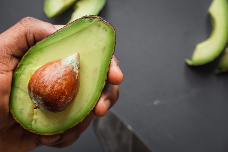 hand holding a slice of avocado