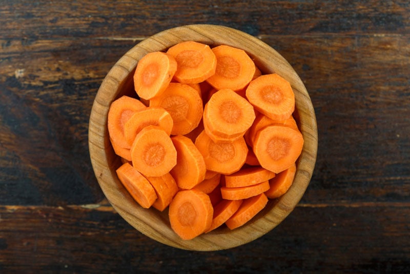 sliced carrots in a bowl on a wooden background