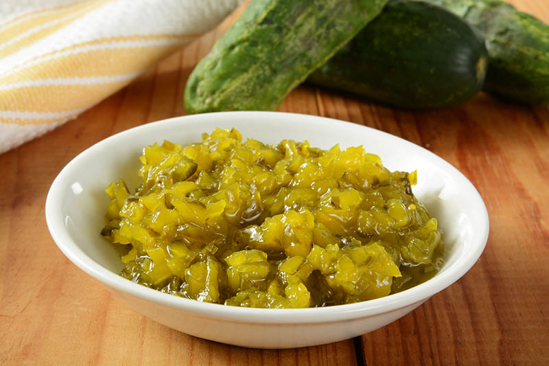 A bowl of relish with Kirby pickling cucumbers in the background