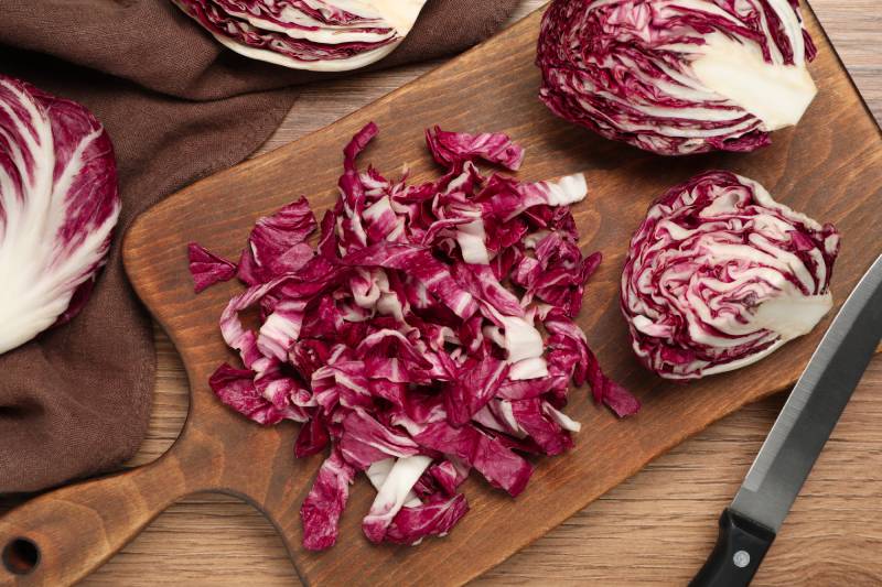 Cut radicchio and knife on wooden table