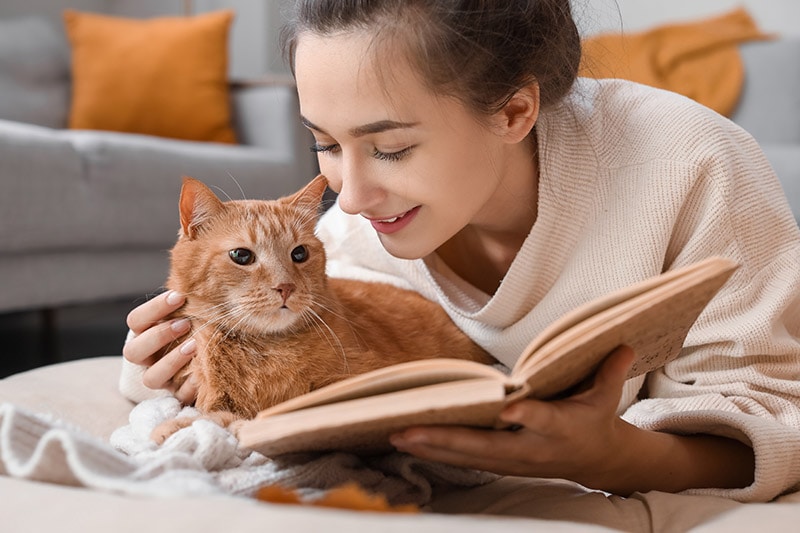 young woman reading with her cat