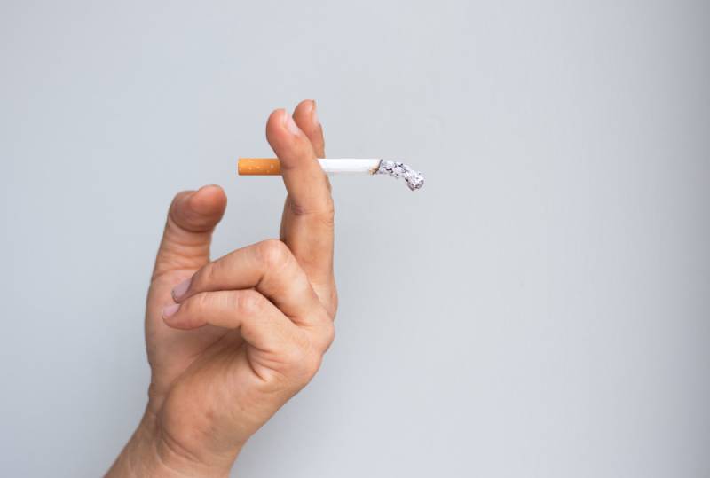 man holding a used up cigarette