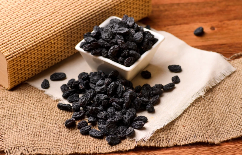 black raisins in a white bowl on canvas cloth