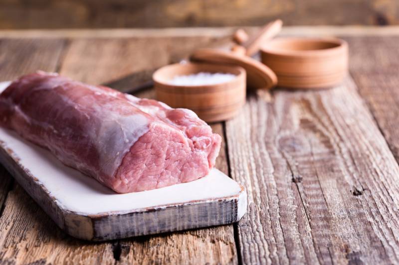 raw pork tenderloin on chopping board raw pork tenderloin on chopping board