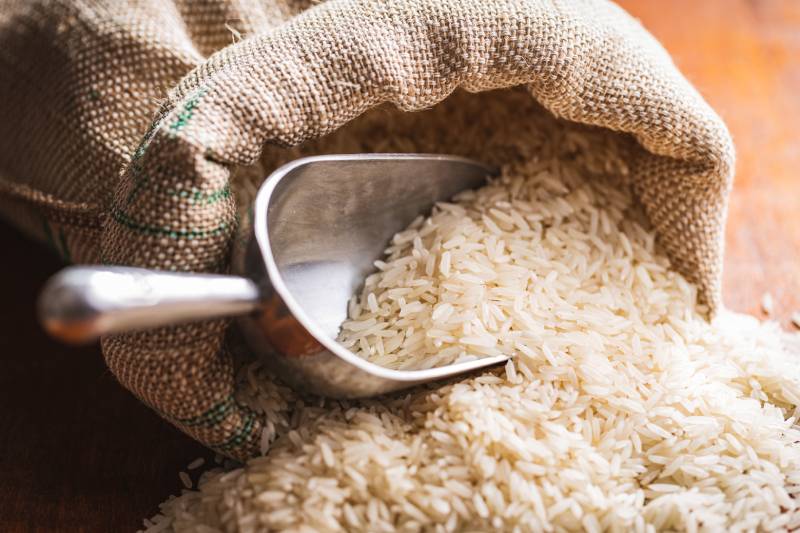 raw uncooked white rice in a sack on wooden table