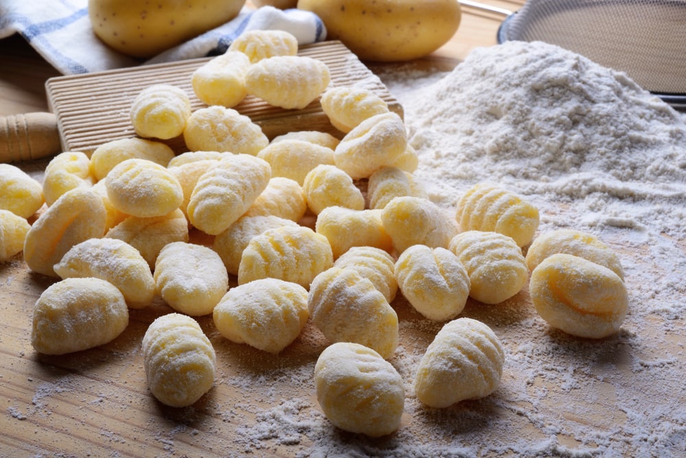 Potato gnocchi with flour on wooden pastry board
