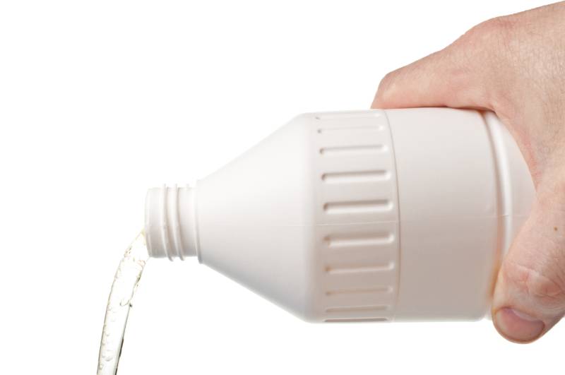 Pouring liquid soap out of a white plastic bottle isolated