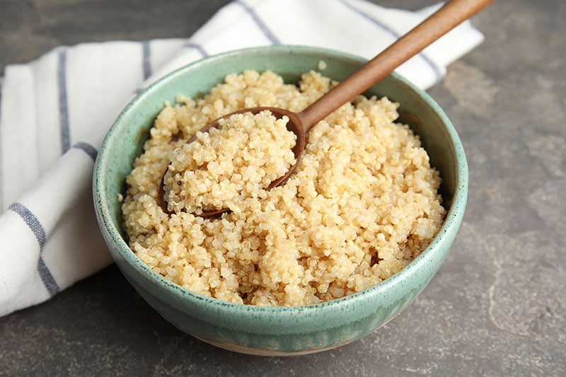 cooked quinoa in bowl and wooden spoon on table